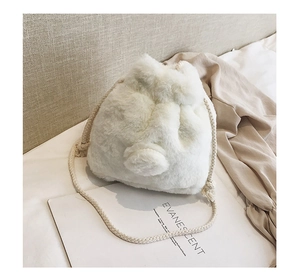 Detail of soft white plush drawstring bucket bag with fluffy pom-pom and braided strap