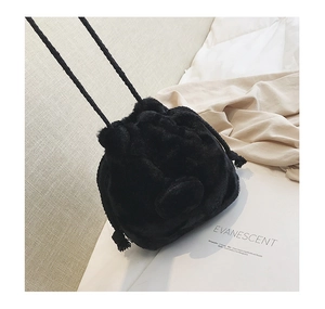 Detail of soft black faux fur bucket bag with drawstring closure and woven strap