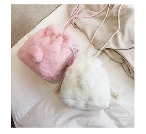 Close-up of winter faux fur bucket bag with drawstring closure and soft pompom detail