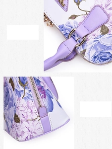 Close-up of floral shell bag with purple roses, gold hardware, and cross-grain leather