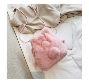 Detailed view of pink plush bucket bag with drawstring closure and soft pom-pom details