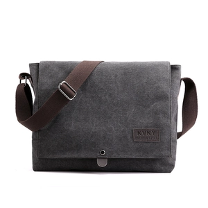 Charcoal grey canvas messenger bag with adjustable brown strap and branded leather patch
