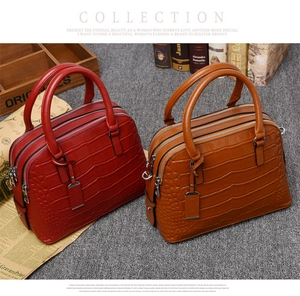 Detail of red and brown crocodile pattern handbags with triple zipper compartments