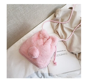 Close-up of pink faux fur bucket bag texture with soft pompom and braided drawstring