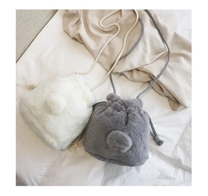 Detail of plush faux rabbit fur texture and drawstring closure on mini bucket bags