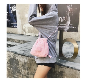 Detail of pink faux fur bucket bag with plush pom-poms and drawstring closure