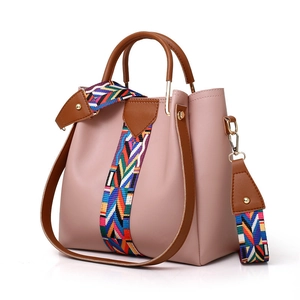Pink bucket handbag with brown trim and colorful bohemian woven shoulder strap