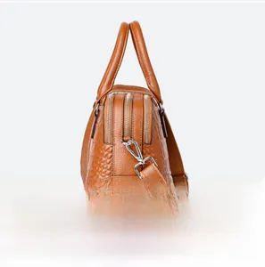 Detail view of crocodile pattern leather handbag showing side profile and zipper compartments