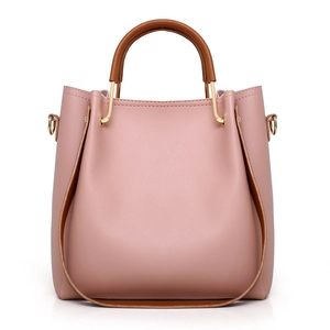 Minimalist nude pink tote bag with brown leather handles and gold metal hardware accents