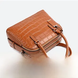 Detail of brown crocodile pattern handbag featuring a dual zipper and silver hardware