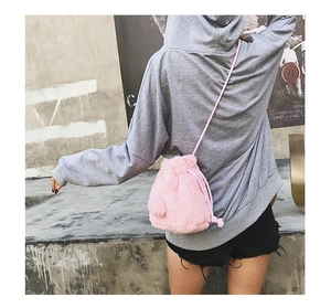 Pink plush drawstring bucket bag with soft faux fur texture shown on a female model crossbody