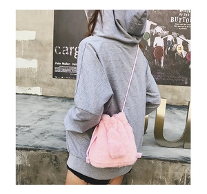Detail of pink faux fur bucket bag with drawstring and fluffy pompom charms