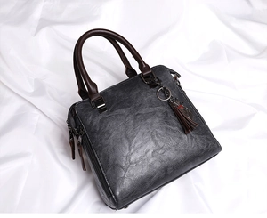 Dettaglio borsa grigia vintage con ciondolo a forma di gatto e nappa marrone decorativa