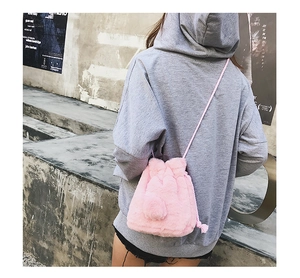 Detail of pink faux fur drawstring bucket bag with fuzzy pom-pom and braided strap