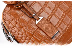 Detail of brown faux crocodile leather texture with silver metal zipper and tag