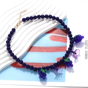 Detailed shot of handmade purple beaded grape and flower pendant necklace with golden clasp