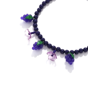 Handmade beaded necklace featuring dark blue beads with purple grape and flower charms