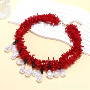 Detail of red branch-like coral elements with white baroque pearl pendants on a golden chain