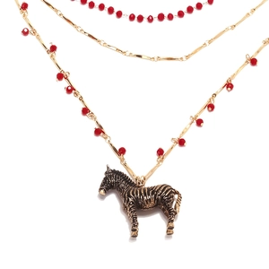 Détail du collier triple rang doré avec perles rouges et pendentif zèbre rétro