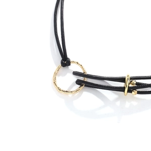 Macro shot of gold geometric metal rings and textured beads on black PU leather rope