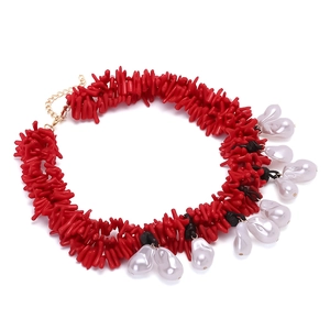Detailed view of woven red coral-style beads with white drop pearl charms and gold clasp