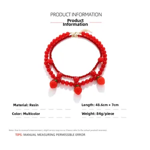 Détail d'un collier à deux rangs avec perles rouges et cinq pendentifs fraises