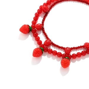 Détail macro du pendentif fraise rouge avec perles multicouches sur un collier élégant