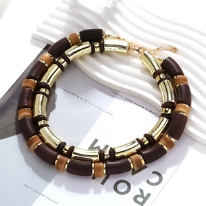 Double-layered necklace with gold metal tubes and brown resin beads on a magazine