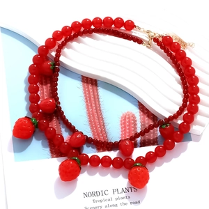 Vue détaillée du collier à perles double couche avec pendentifs fraises et fermoir doré