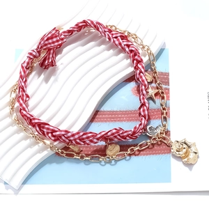 Detail of red checkered woven cord and gold necklace with starfish and seashell charms