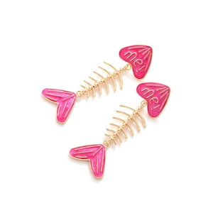 Detailed shot of pink enamel fishbone earrings with heart accents and me lettering