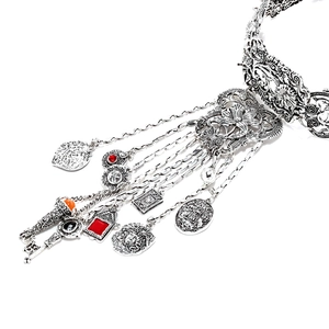 Détail macro du collier argenté vintage avec relief Méduse, pierres rouges et pendentifs