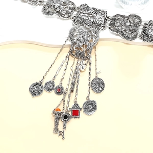 Détail d'une chaîne de taille argentée vintage avec fleurs et pendentifs pièces