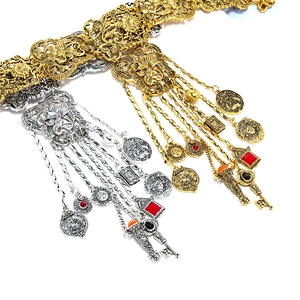 Gros plan sur les pendentifs pièces vintage et pompons d'un collier à fleurs