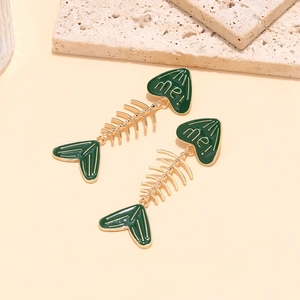Detailed macro shot of dark green enamel fishbone earrings with golden metal accents