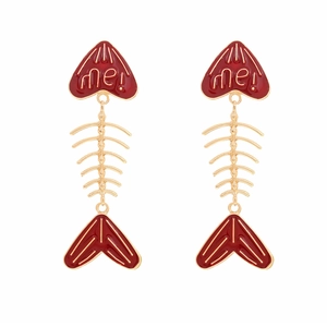 Detailed close-up of gold alloy fishbone earrings with red enamel and me! lettering