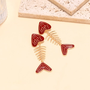 Detail of gold fishbone earrings with red enamel hearts and me! lettering