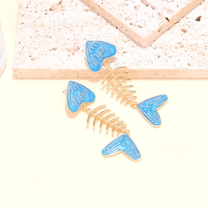 Macro detail of blue enamel fishbone earrings with me! lettering and gold finish