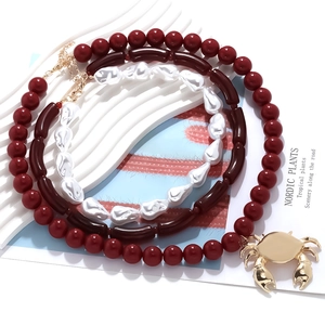 Layered beaded necklace with red beads, baroque pearls and large gold alloy crab pendant