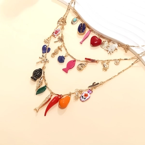 Gros plan d'un collier doré avec breloques émaillées colorées de poisson et de cœur