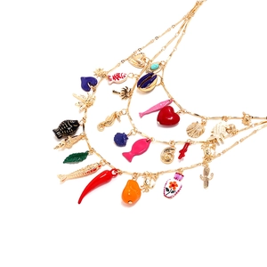 Détail d'un collier bohème multicouche avec des breloques émaillées en forme de poisson