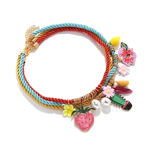 Colorful multi-layer braided rope necklace with strawberry and cactus charms on white background