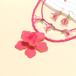 Dettaglio della collana di perline rosa con ciondoli floreali e orecchini abbinati
