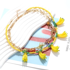 Détail du collier d'été perlé avec pendentifs banane et accents de fleurs et papillons