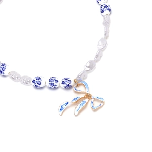 Detail view of baroque pearls and blue floral ceramic beads with bow pendant