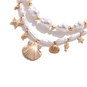 Dettaglio della collana di perle barocche con ciondoli dorati a forma di conchiglia e stella