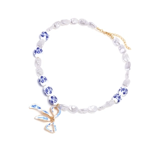 Baroque pearl necklace with blue and white porcelain bow pendant and gold accents
