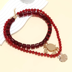 Collier double rang de perles rouges avec pendentifs crabe et coquillage dorés