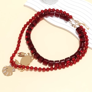 Vue détaillée du collier double rang perlé avec breloques crabe et coquillage dorées