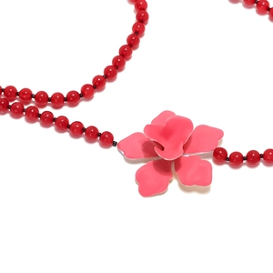Übertriebene rote Perlenkette mit einem großen, lebhaften rosa Blumenanhänger